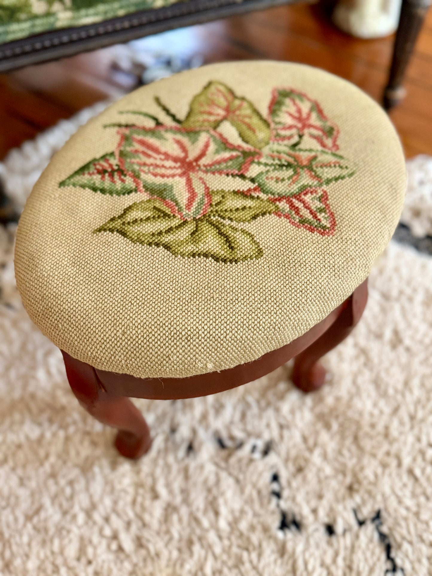 oval needlepoint footstool with pink and green leaf design