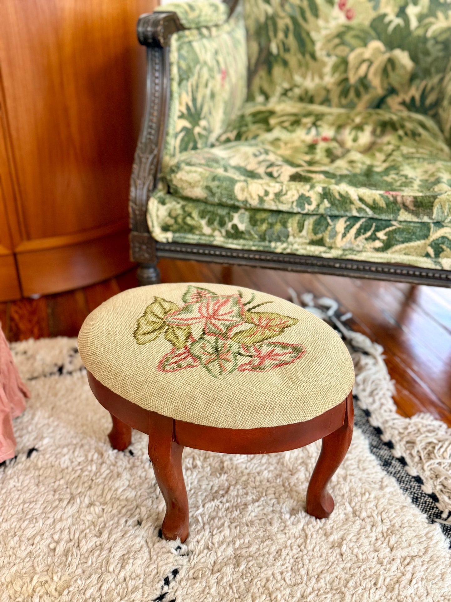oval needlepoint footstool with pink and green leaf design